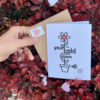 hand holding floral encouragement card in front of red leaves