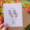 hand holding birthday card with flowers and qr code that plays Hooray It's Your Birthday Card
