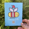 Bees on Earth recycled paper singing greeting card held by hand in front of greenery