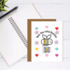 galenting and friendship card with bee, hearts, flowers and qr code that plays original friendship song shown on desk wtih notebook in background