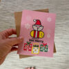 hand showing pink Bee Merry holiday card and envelope