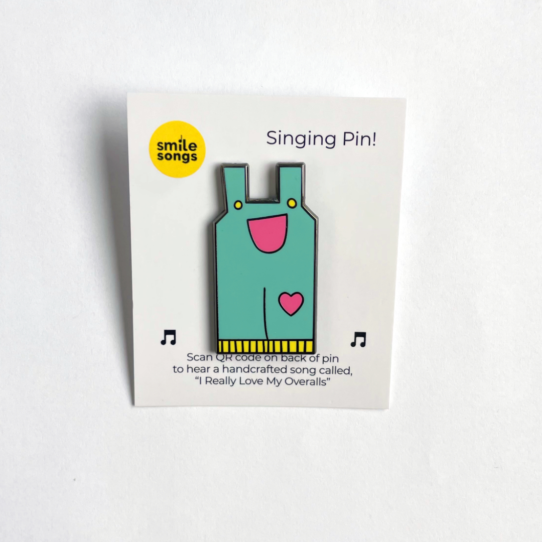 blue overalls enamel lapel pin with smile and heart shaped knee patch on backing card