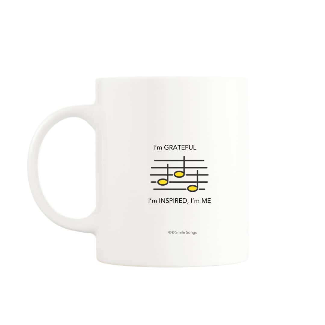 Back of white mug featuring a lyric excerpt and musical notes, enhancing the Grateful, Inspired I'm Me design on front