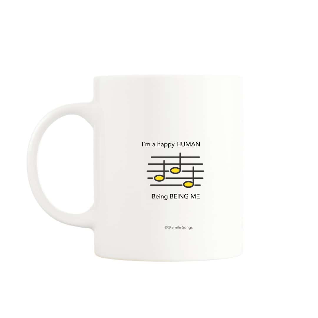 White mug featuring a lyric excerpt with musical notes on the back, complementing the Happy Human design