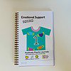 Emotional Support Squad interactive journal with cover featuring team jersey with number 1 and flying hearts, bellyband with QR code that sings song about what the journal is and does